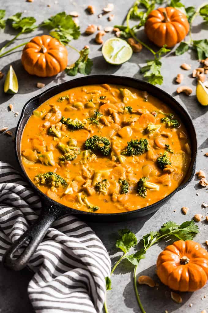 Side view of Pumpkin Thai Curry in a cast iron skillet with mini pumpkins around it.