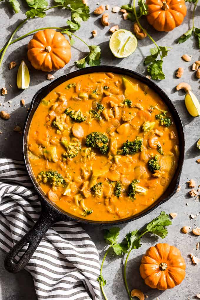 Pumpkin Thai Curry in a cast iron skillet with mini pumpkins around it.