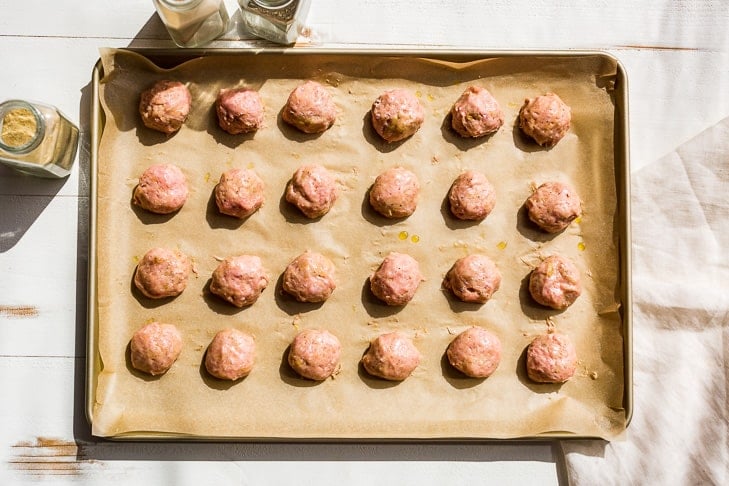 Portioned out turkey meatballs on a parchment lined cookie sheet.