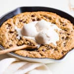 Chocolate Chip Skillet Cookie with ice cream on top and a wooden spoon scooping some out.
