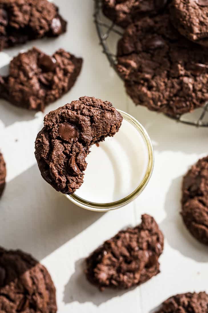 Half of a chocolate cookie sitting on a glass of milk.