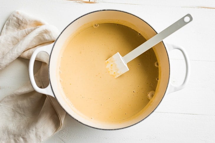 Stirring the maple ice cream custard in a large pan with a spatula.