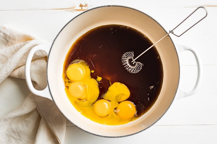 Egg yolks and maple syrup in a large pan with a whisk.