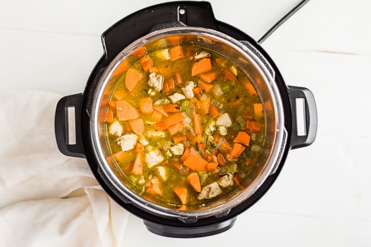 Adding the chicken stock as the final step before cooking, making sure all the ingredients are pressed down under the liquid.