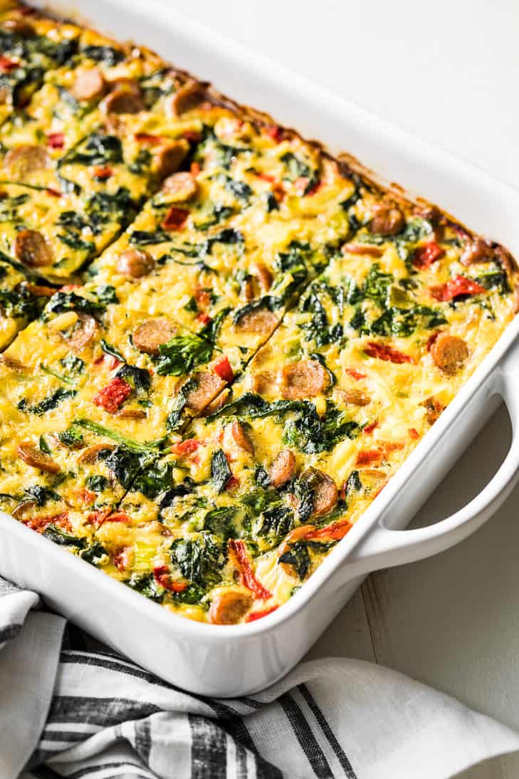 Make ahead breakfast casserole with sausage and hash browns in a white baking dish.