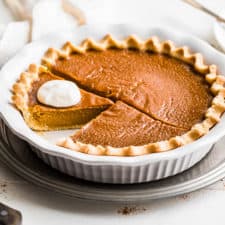 Finished photo of the pumpkin pie with slices and whipped cream.