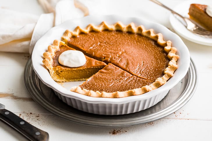 Finished photo of the pumpkin pie with slices and whipped cream.