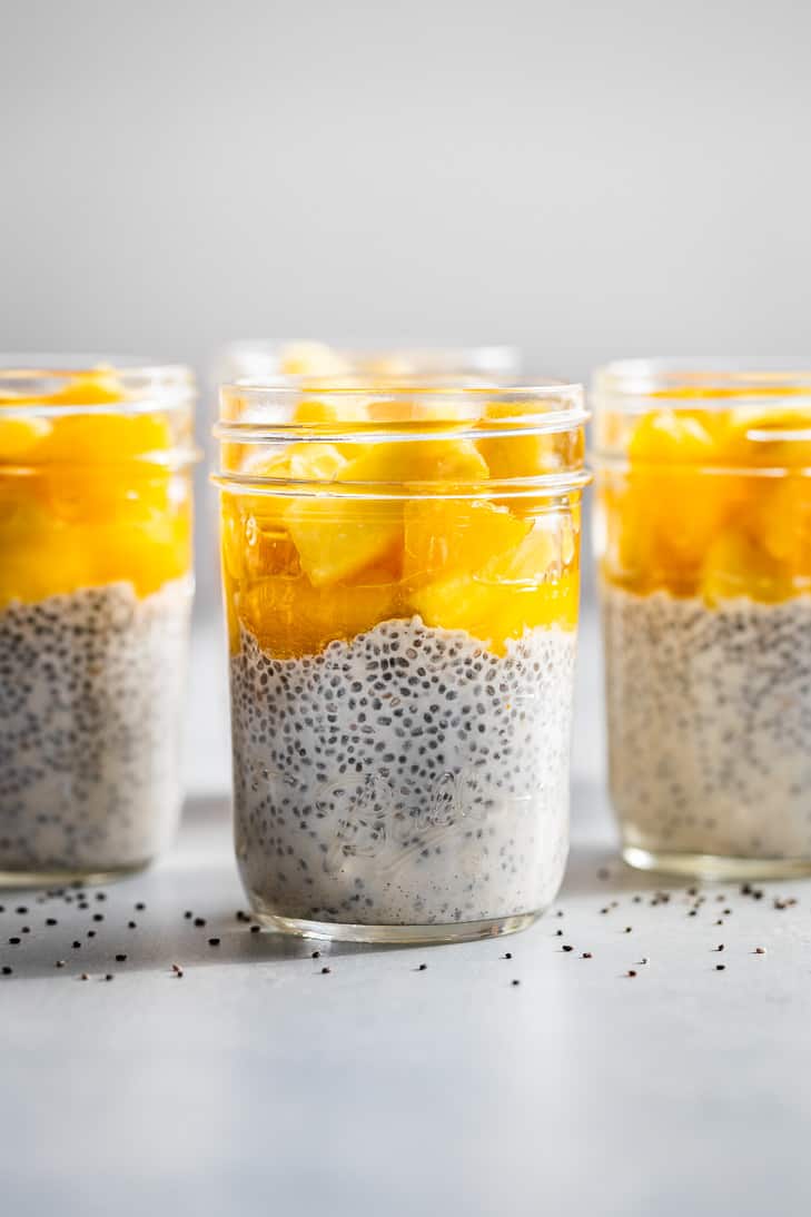 3 mason jars of creamy coconut chia pudding topped with tropical fruit.