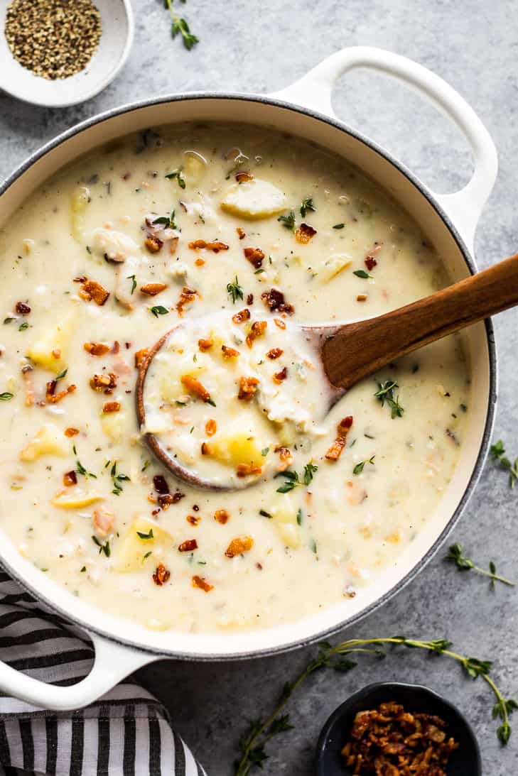 A large white soup pot with Creamy Dairy Free Clam Chowder and a striped linen.