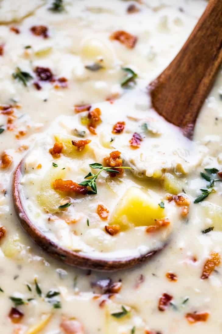 A large wooden ladle dipped into the pot of Creamy Dairy Free Clam Chowder.