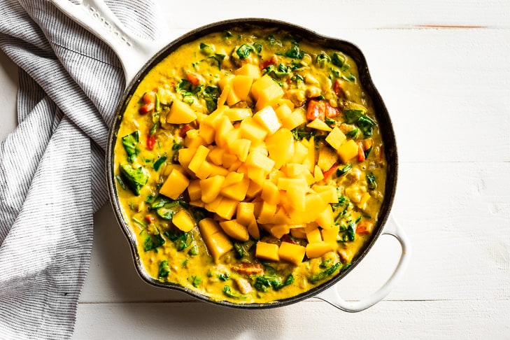 The final step of adding the fresh mango to the skillet right before serving.