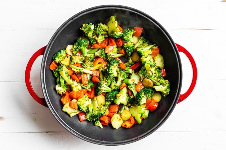 Veggies for the cashew chicken being stir fried in a red skillet.