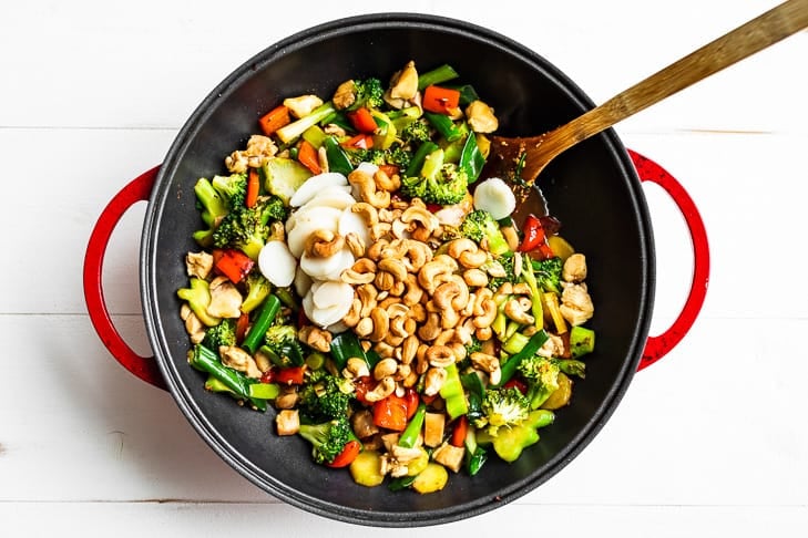 Adding the last few ingredients to the cashew chicken.