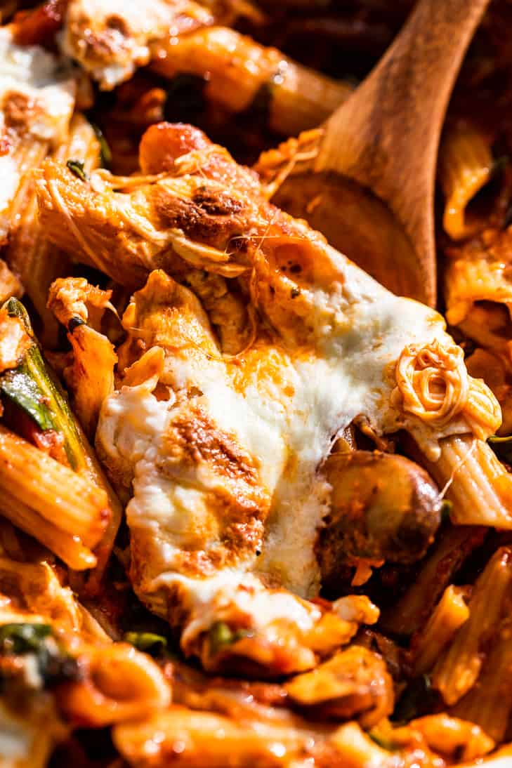 Up close view of the pasta bake being scooped out with a wooden spoon.