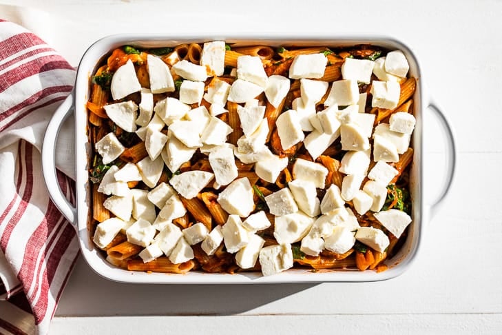 Pasta mixed into the tomato sauce and placed in a baking dish and topped with fresh mozzarella.