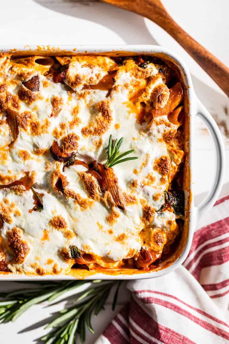 Simple Veggie Pasta Bake in a white baking dish with a red and white linen and wooden spoon.
