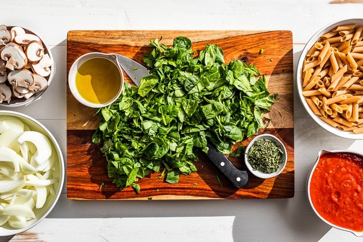 All the ingredients for the Simple Veggie Pasta Bake prepped on a wooden cutting board.