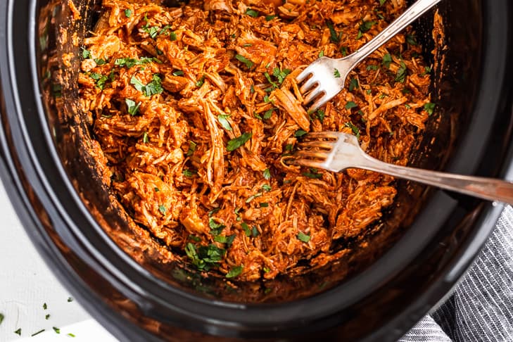 Shredding the finished Slow Cooker Chipotle Chicken with forks.