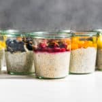 5 of the 10 Overnight Oats flavors on a white background and grey backdrop, (tropical, blueberry almond, PBJ, creamsicle, and carrot cake).