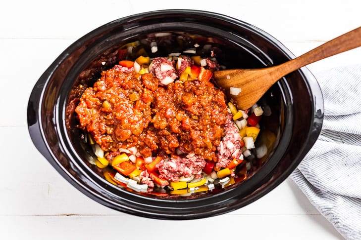 Adding the salsa to the slow cooker bowl over the ground beef mixture.