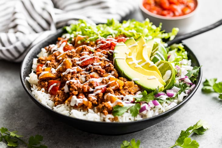 A 'taco bowl' made with salsa beef piled over rice with toppings.