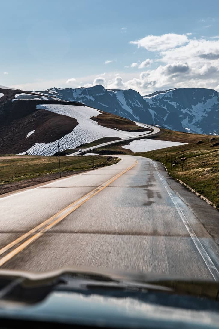 A passenger side view through the windshield looking at the Beartooth mountain area while driving.