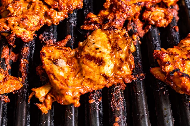 Marinated chicken thighs on the grill.