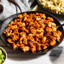 A bowl of Copycat Chipotle Chicken with the burrito bowl toppings around it.