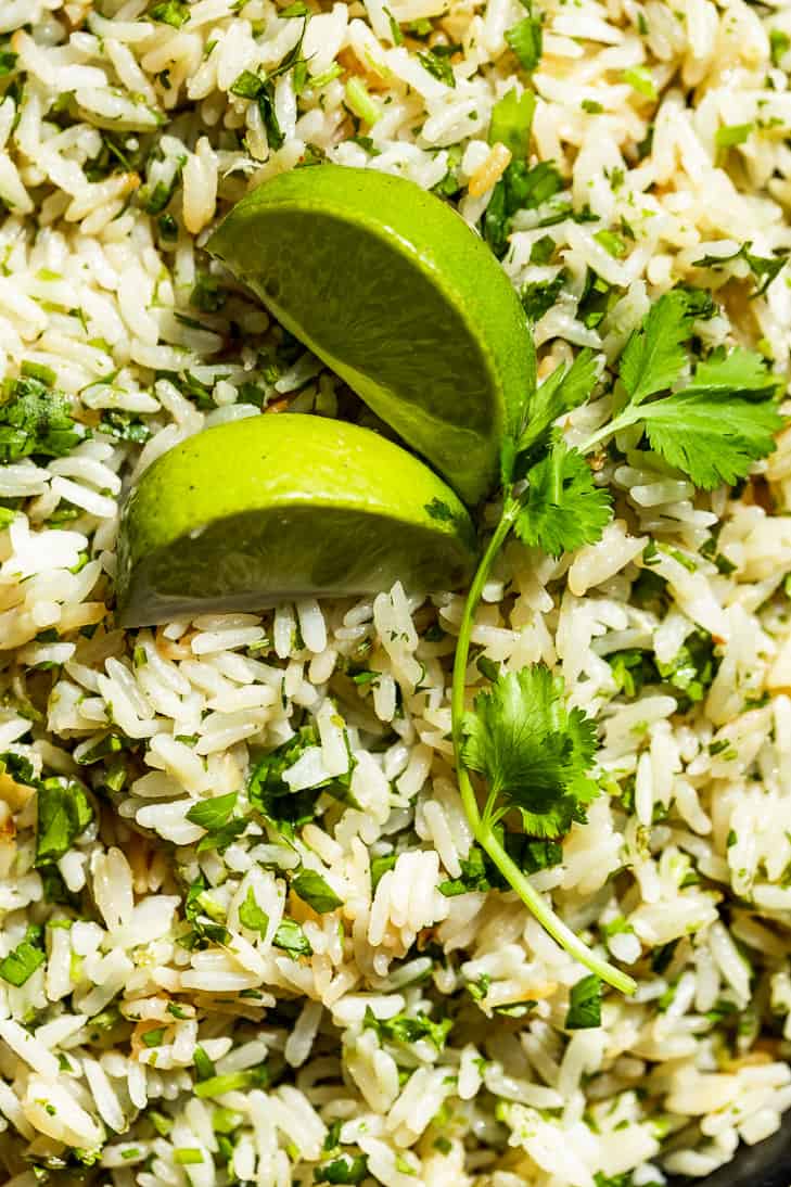 Up close view of cilantro lime rice with two lime wedges on top.