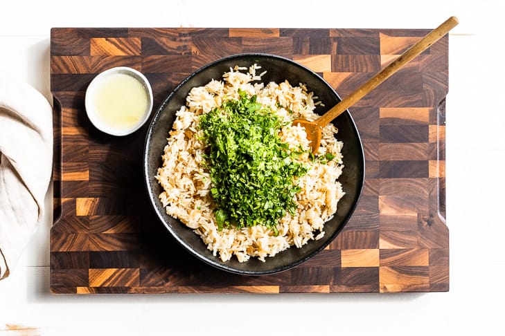 The cilantro, lime zest, and lime juice being added to the cooked rice.