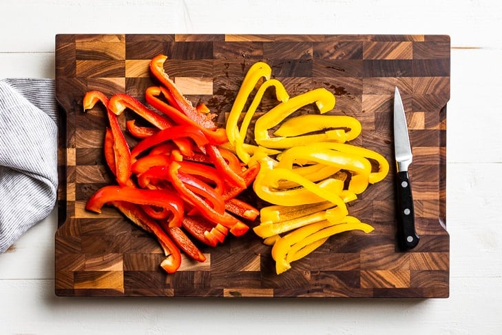 Cutting up the peppers for the fajita veggies on a wooden cutting board.