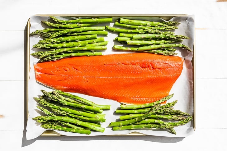 The salmon and asparagus on a parchment lined baking sheet.
