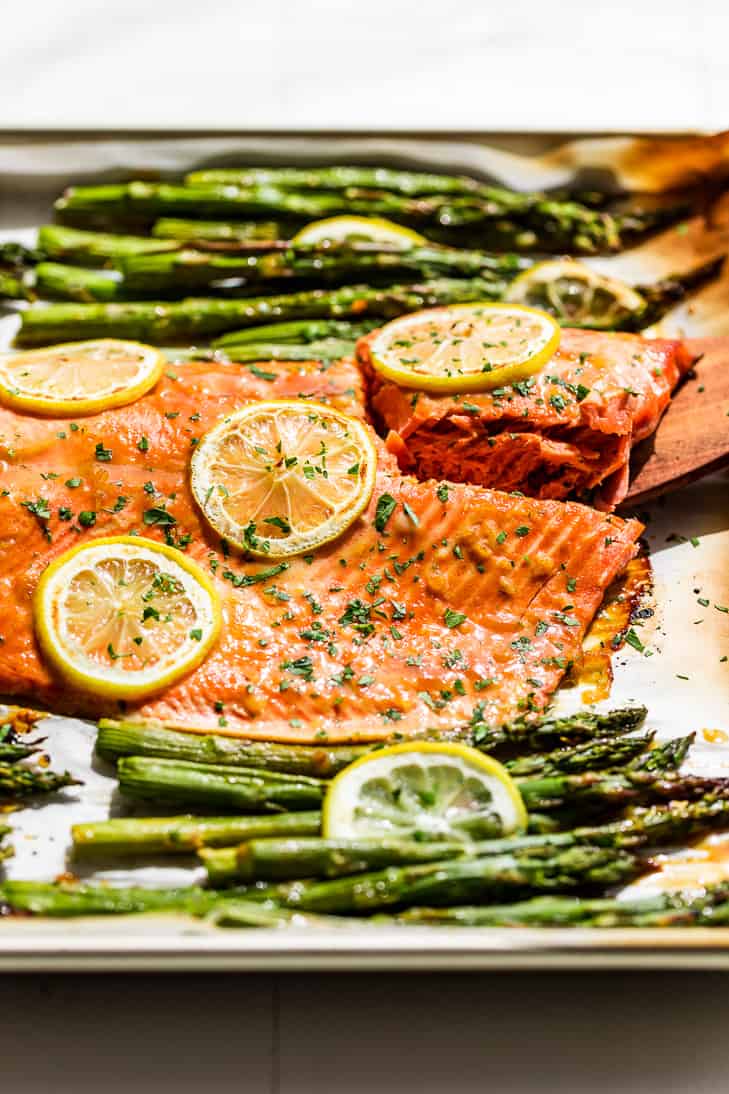 A side view of the Honey Dijon Salmon and Asparagus on a sheet pan with lemon slices.