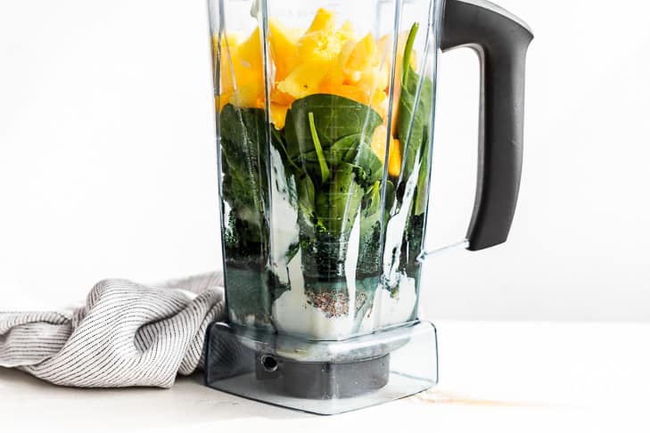 All of the Pineapple Green Smoothie ingredients layered into a blender.
