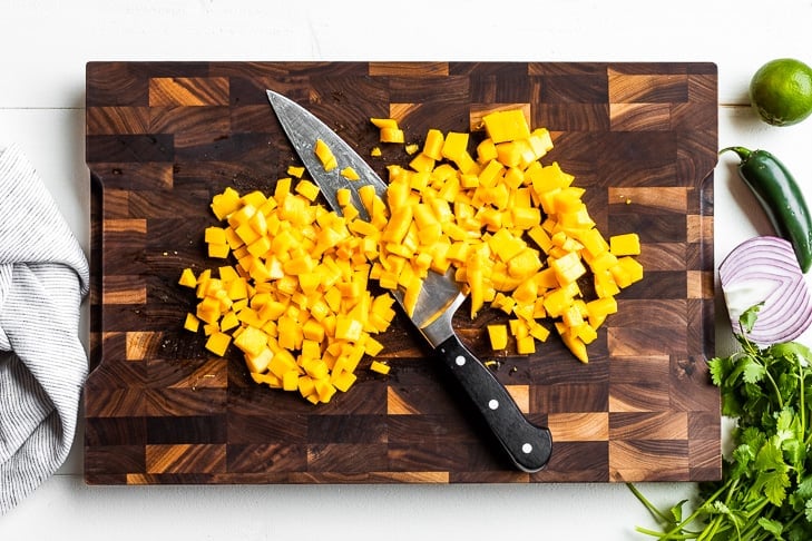 Diced mango on a wooden cutting board.