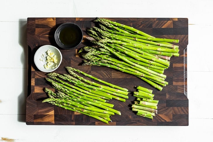 Removing the ends of the asparagus on a wooden cutting board.