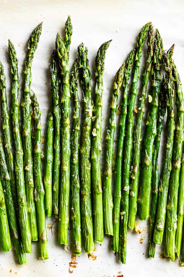A close up view of roasted asparagus on parchment paper.