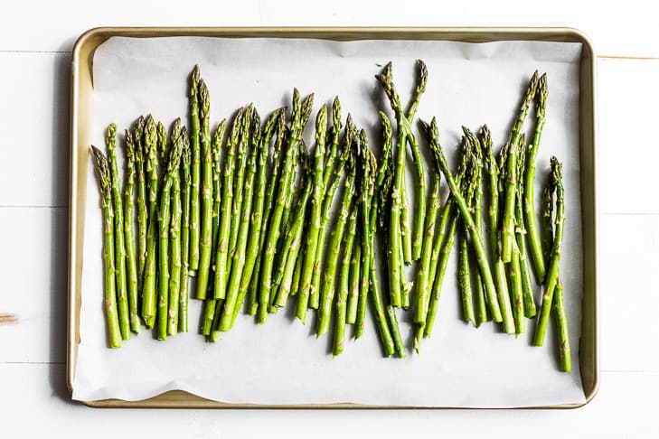 The trimmed asparagus on a parchment lined baking sheet.