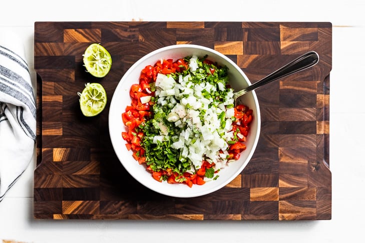 Diced onion, jalapeno, and cilantro being added to the diced tomatoes.