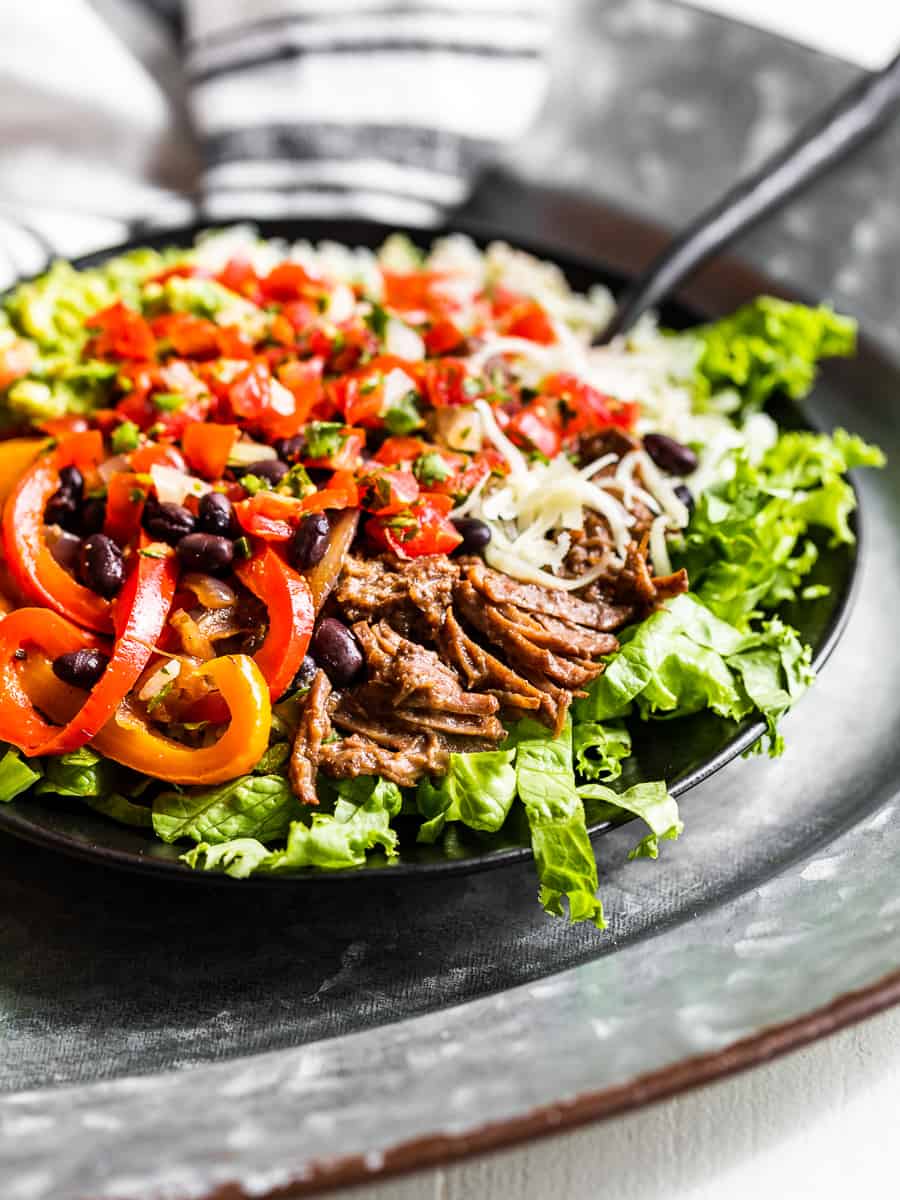 Barbacoa Burrito Bowl on a metal tray with a blue and white striped linen.