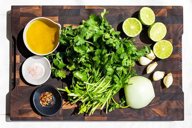 All the ingredients for the Cilantro Chimichurri on a wooden cutting board.