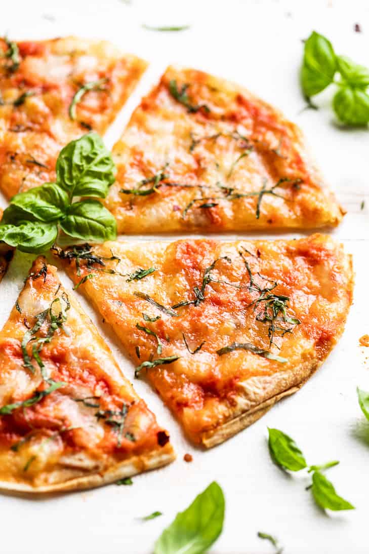 A side view of Grilled Tortilla Pizza Margherita with basil around it.