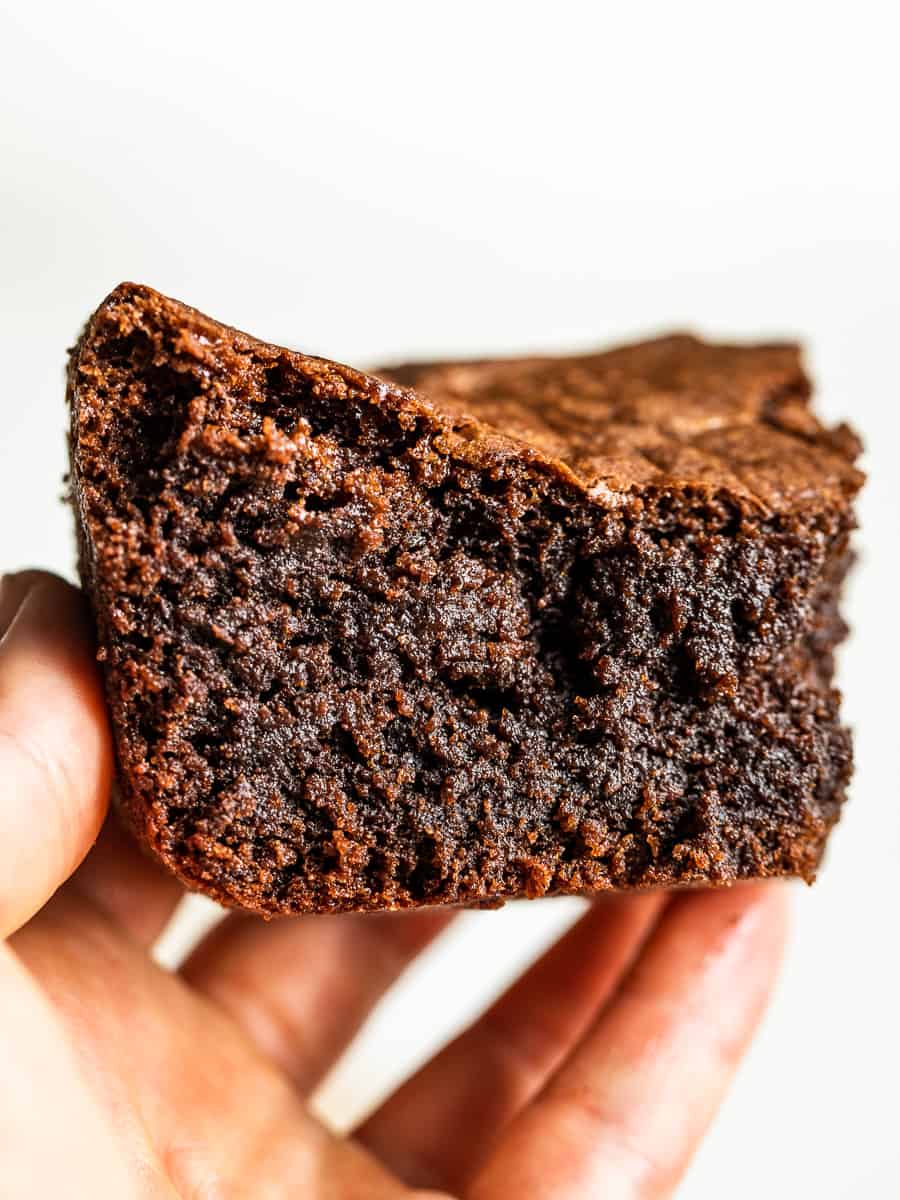The Best Flourless Brownies held in a hand against a white background.