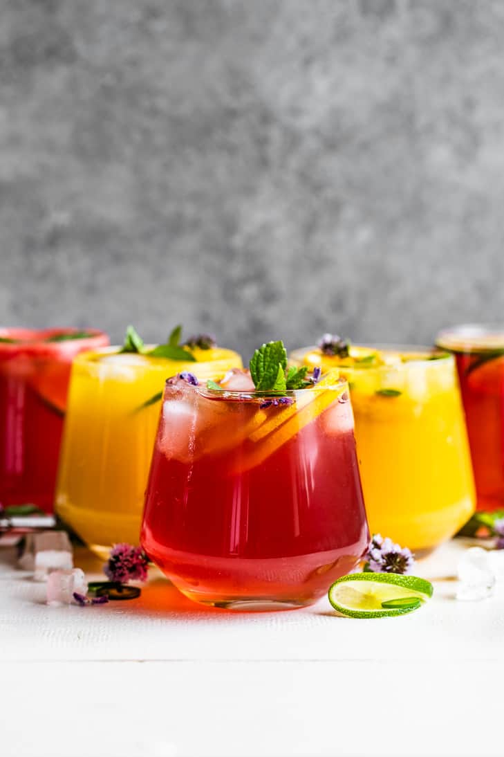 2 orange, and 3 red colored mocktails on a white background.