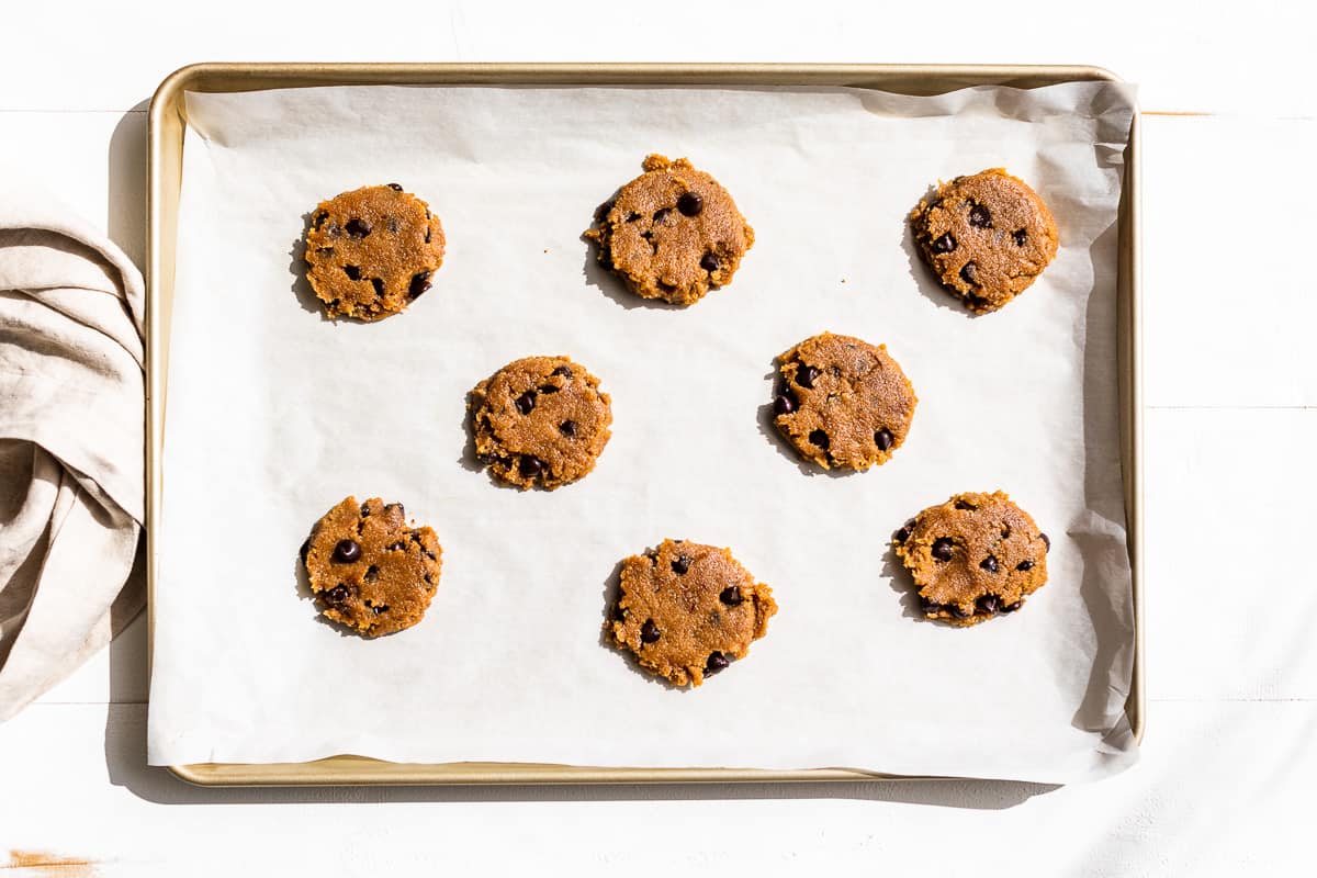 Flattened cookie dough on a parchment lined baking sheet.