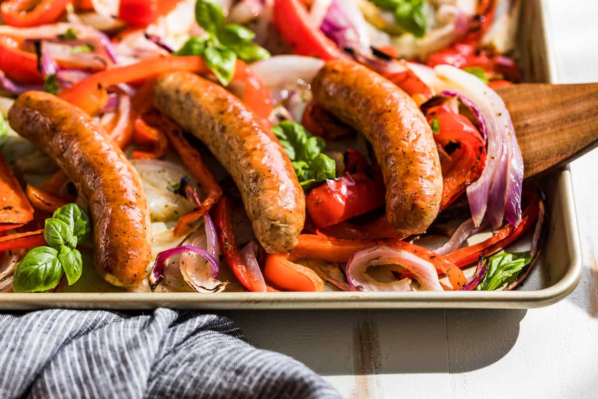 Sausage with peppers and onions garnished with basil.