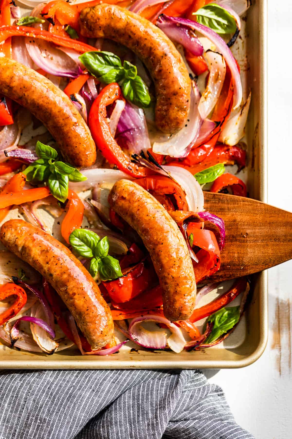 Straight down view of Sausage and peppers with a wooden spatula.