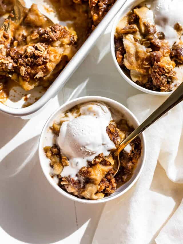 Two bowls of Gluten Free Apple Crisp topped with vanilla ice cream.