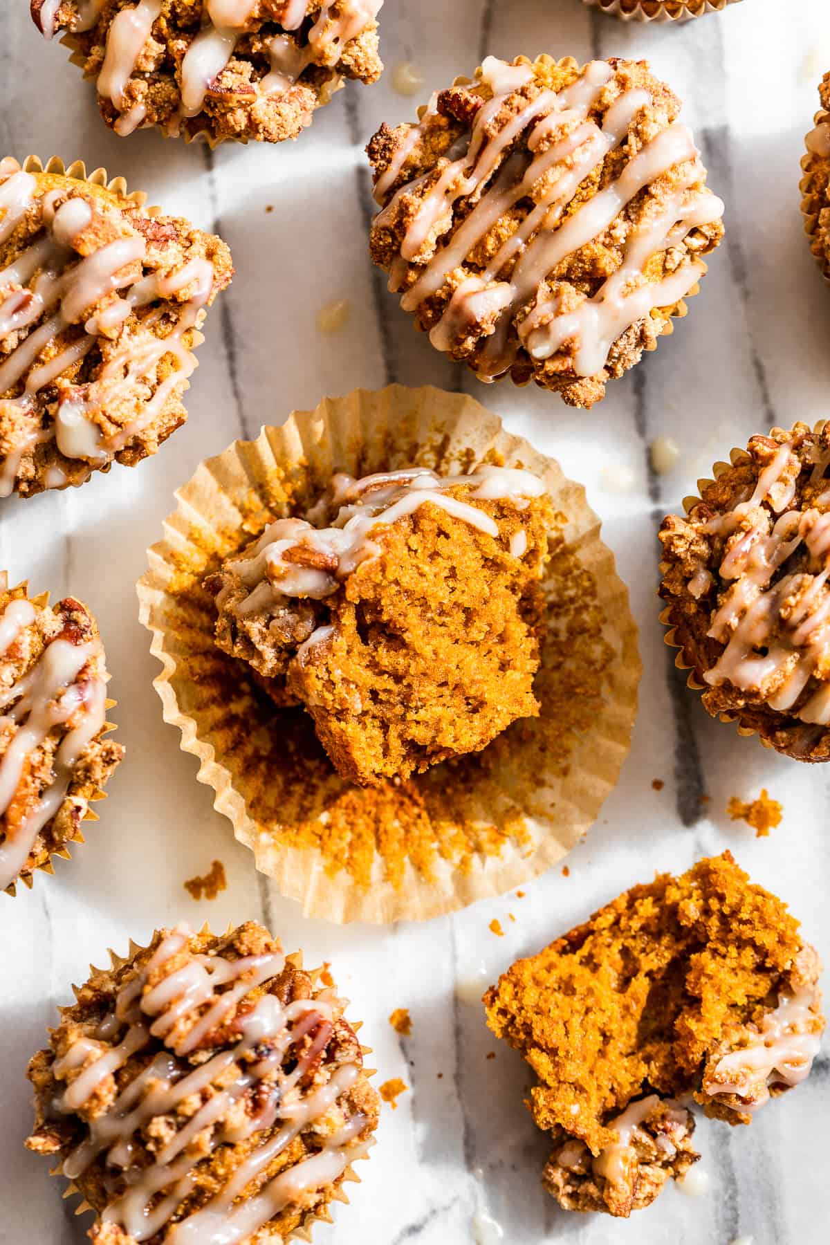 Almond Flour Pumpkin Muffins on a marble background with 1 muffins split in half.