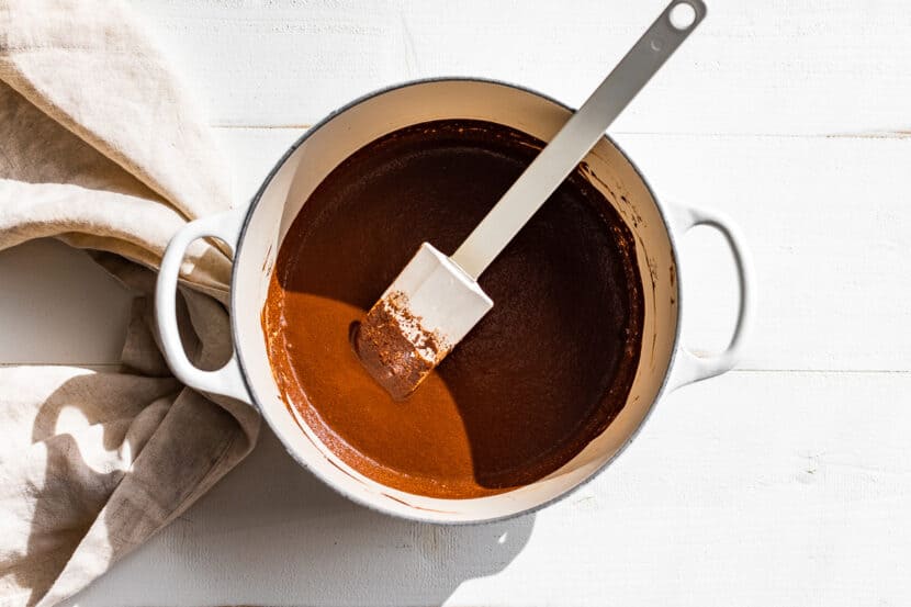 Cocoa powder and maple syrup being mixed together in a white pan.
